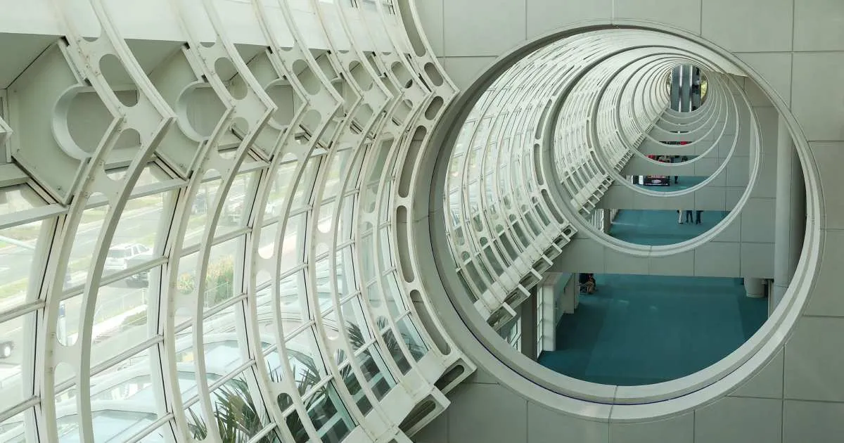 Looking along a row of circular concrete openings and curved white steel and glass framing inside the San Diego Convention Center.