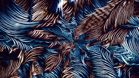Close-up of crushed metallic material in blue and copper tones, its ridged folds fanning out from the center.