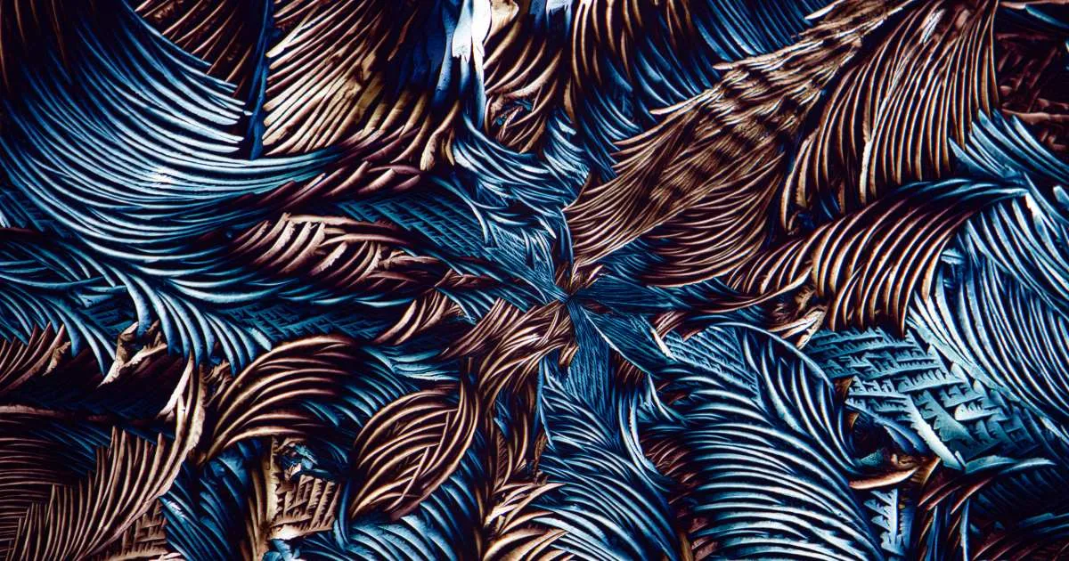 Close-up of crushed metallic material in blue and copper tones, its ridged folds fanning out from the center.